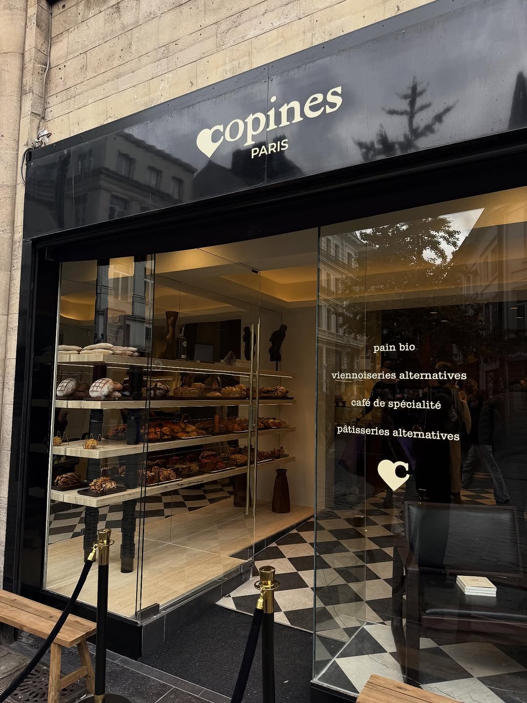 Entrée de la boulangerie Copines Paris à Bruxelles, design épuré en noir et blanc avec étagères remplies de pains et viennoiseries bio